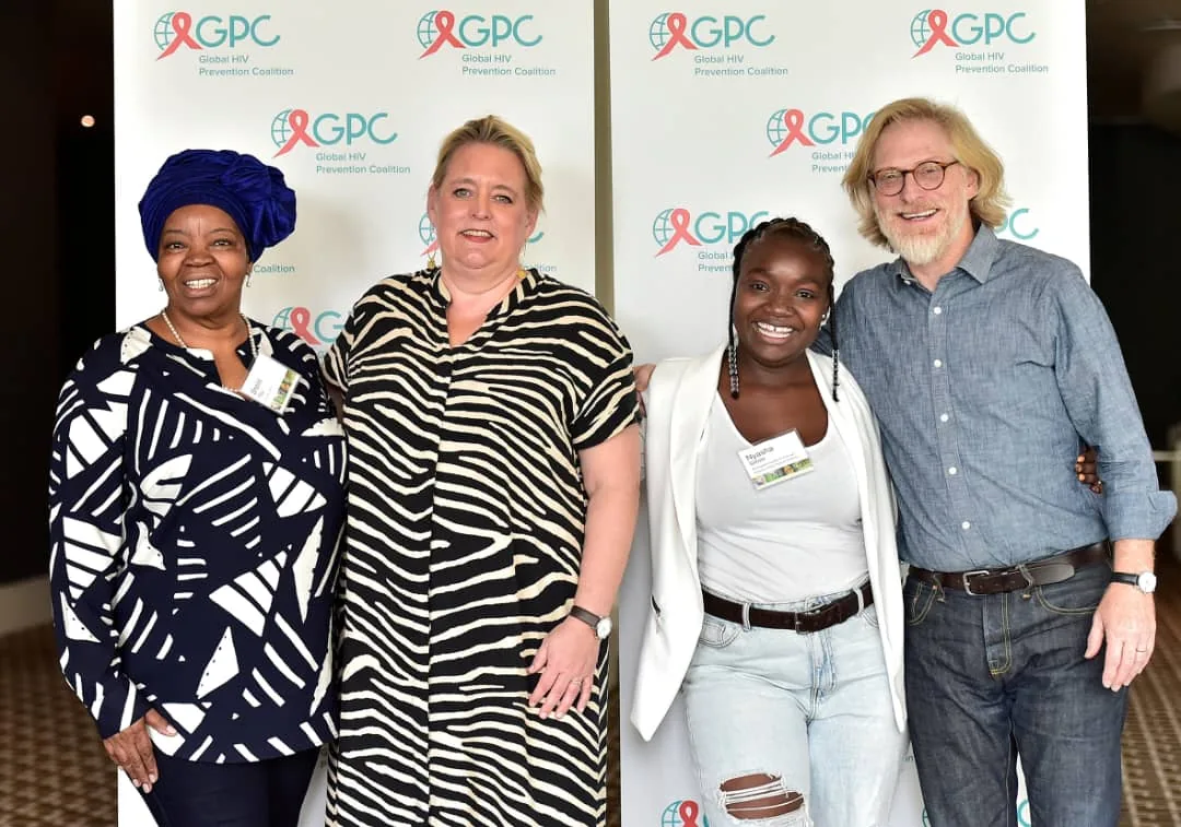 Professor Sheila Tlou standing with colleagues before a Global HIV Prevention Coalition backdrop.